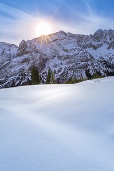 A lovely winter day in the Austrian Alps mountains from the Ehrwald municipality, with the rocky peaks and snowy pastures warmed up by a bright and colorful sun.