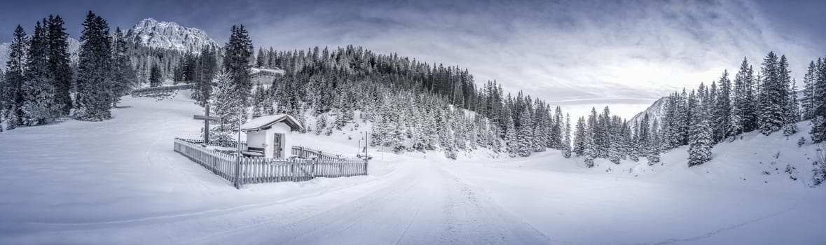 Idyllic winter panorama with a snowy forest and a small chapel, called "Pestkapelle", build in 1639 as a thank you for the end of a plague. Landscape caught in the Austrian alpine forests, the Ehrwald resort.