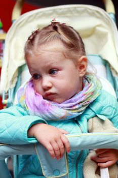 Dissatisfied little girl in a pushchair