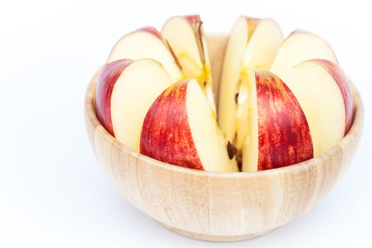 Sliced apple in wooden bowl on white background