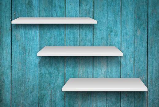 Three white shelves on blue wooden texture background, stock photo