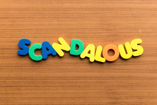 scandalous colorful word on the wooden background