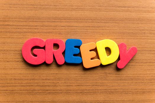 greedy colorful word on the wooden background