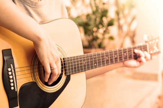 Woman's hands playing acoustic guitar with vintage style, stock photo