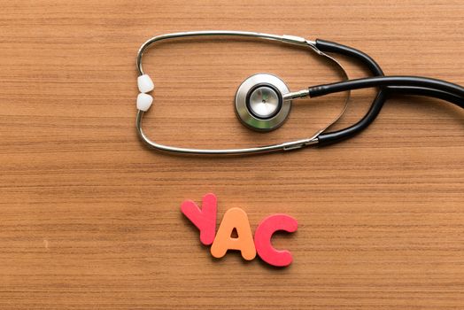 yac colorful word with stethoscope on wooden background