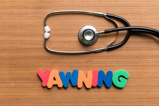 yawning colorful word with stethoscope on wooden background