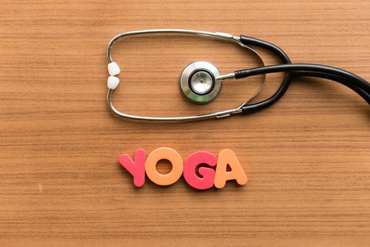 yoga colorful word with stethoscope on wooden background