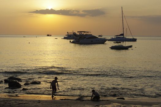 Silhouette of sailing boats on the horizon against famous beautiful sunset on tropical exotic white beach on Phuket island, Thailand