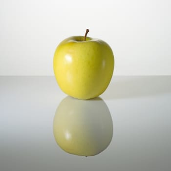 Green elastic apple on a surface with reflection