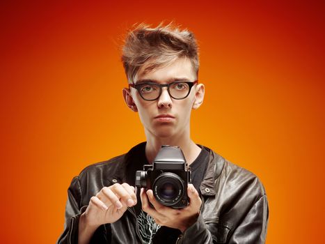 Emotional portrait of a teenager  with film camera on a red background