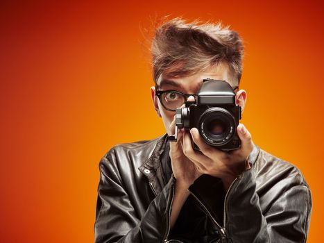 Emotional portrait of a teenager  with film camera on a red background