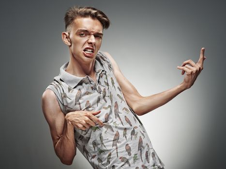 Emotional portrait of a teenager  playing on air guitar on a gray background