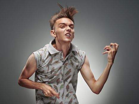 Emotional portrait of a teenager  playing on air guitar on a gray background