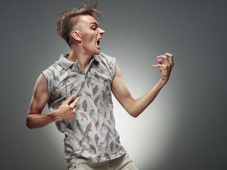 Emotional portrait of a teenager  playing on air guitar on a gray background