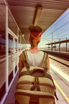 Young sexy woman backpacker waiting for train on platform on railway station. Travel concept. Travel concept.