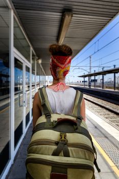 Young sexy woman backpacker waiting for train on platform on railway station. Travel concept.