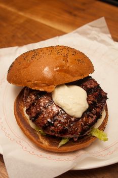 Fresh burger with beef and pork and special sauce closeup on wooden table.