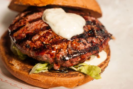 Fresh burger with beef and pork and special sauce closeup on wooden table.