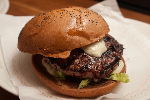 Fresh burger with beef and pork and special sauce closeup on wooden table.