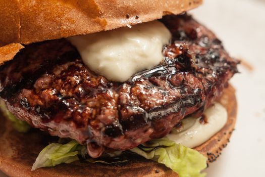 Fresh burger with beef and pork and special sauce closeup on wooden table.