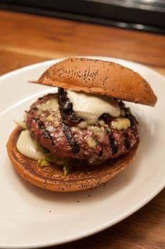 Fresh burger with beef and pork and special sauce closeup on wooden table.