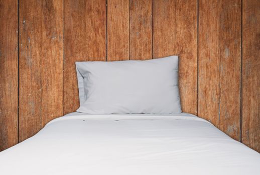 Close up white bedding and pillow on wooden texture background, stock photo