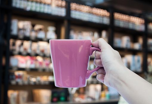 Woman hand holding coffee cup on blurred background, stock photo