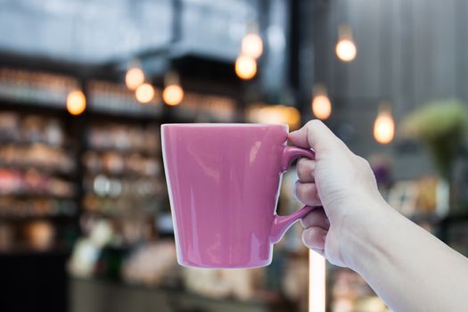 Woman hand holding coffee cup on coffee shop blurred background, stock photo