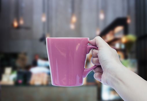 Woman hand holding coffee cup with blurred background, stock photo