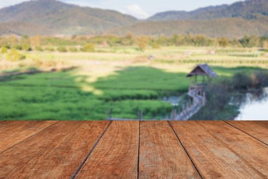 Perspective wooden with green rice field blurred background, stock photo