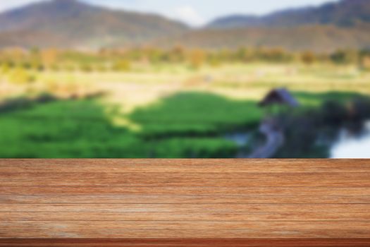 Tabletop wooden with green rice field blurred background, stock photo