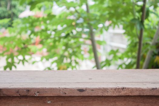 Empty wooden table with blur green leaves bokeh background