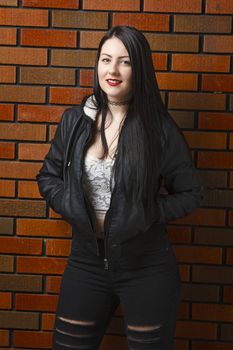 trendy twenty something woman wearing a lace top and a coat in front of a brick wall