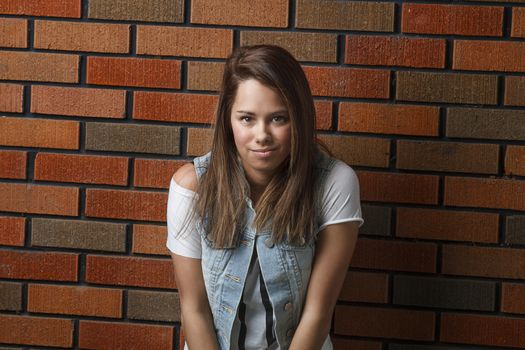 twenty something girl standing against a brick wall