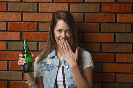 teen girl with surprise look, holding a green bottle of beer