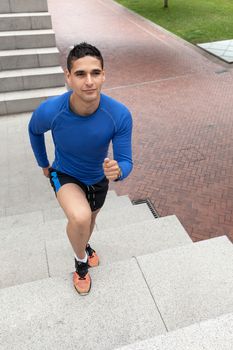 Young athlete wearing blue shirt and pants training climbing stairs