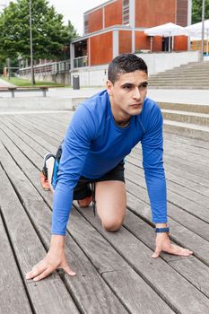 Young athlete in starting position sprint trainning in a wood floor outdoor