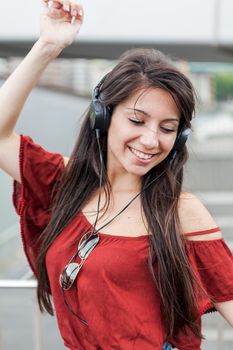 Young girl long brunette hair, smiling listening music and dancing wearing a red blouse