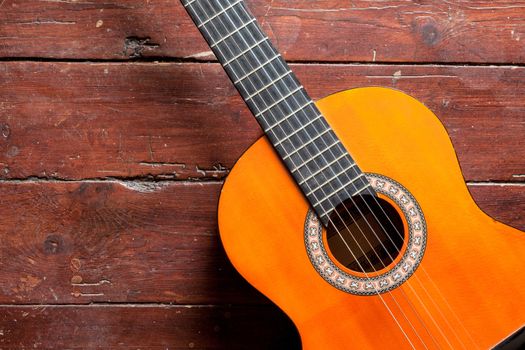 Flamenco guitar on wood background illuminated by natural daylight
