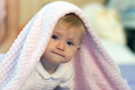 Smiling baby boy under blanket.