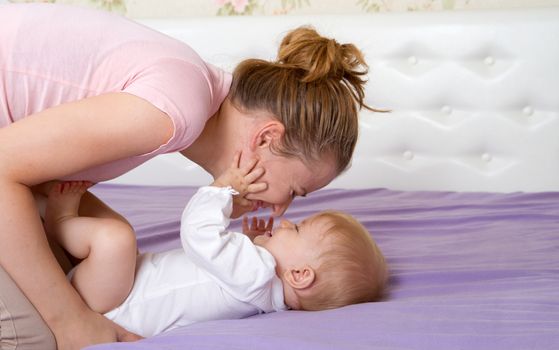 Mum plays with little girl on a bed