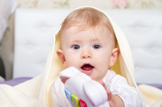 Smiling baby boy under blanket.