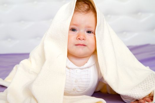 Smiling baby boy under blanket.