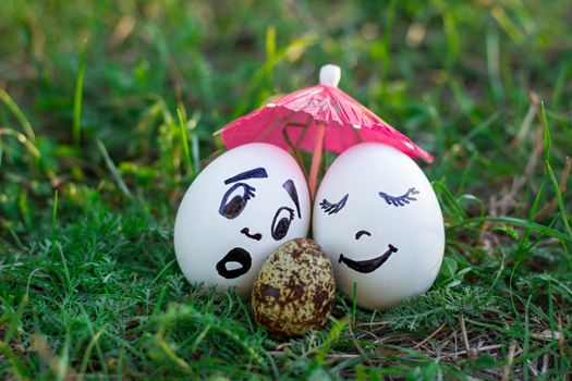 Funny eggs imitating couple of white parents with versicolored baby