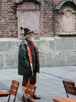 Munich, Germany - November 2011. Man in national dress Tyroleans stands on the street with a hat with a feather