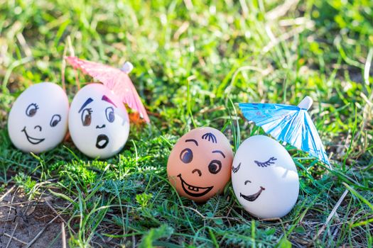 Funny eggs under umbrellas imitating happy mixed couple and indignant white couple