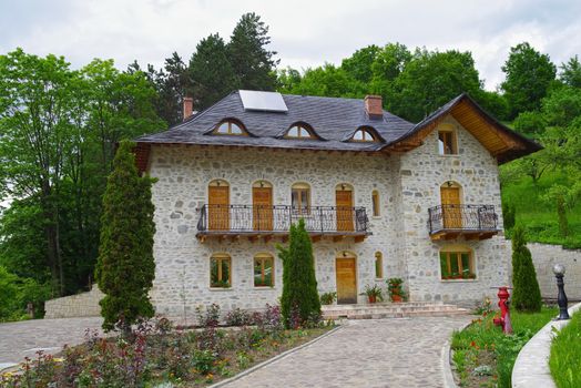 Stone house design near forest with a garden in front.