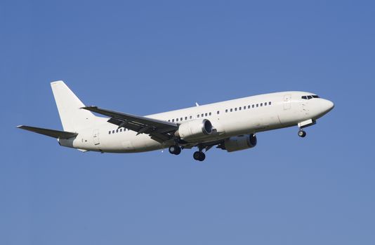 White landing airplane over the blue sky.