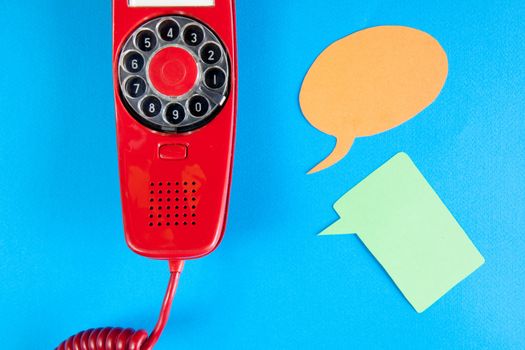 Vintage red phone and speech ballons on blue background