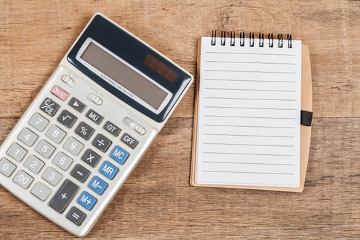 notebook showing empty page  and calculator on wooden desk